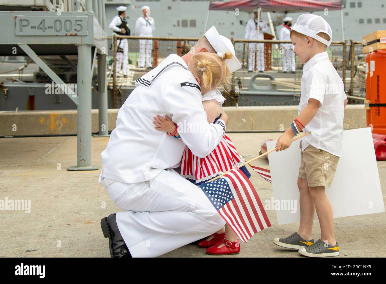 June 28, 2023 - San Diego, California, USA - A Sailor assigned to Arleigh Burke-class guided-missile destroyer USS Decatur (DDG 73) hugs his family after the ship arrived pierside at Naval Base San Diego June 28, 2023. Decatur, a part of Nimitz Carrier Strike Group, returned following a seven-month deployment to U.S. 3rd and 7th Fleet areas of operations. While on deployment, Nimitz Strike Group conducted operations in U.S. 7th Fleet including: deterrence and presence operations; multinational exercises; integrated multi-domain training; long-range maritime strike exercises; anti-submarine war Stock Photo