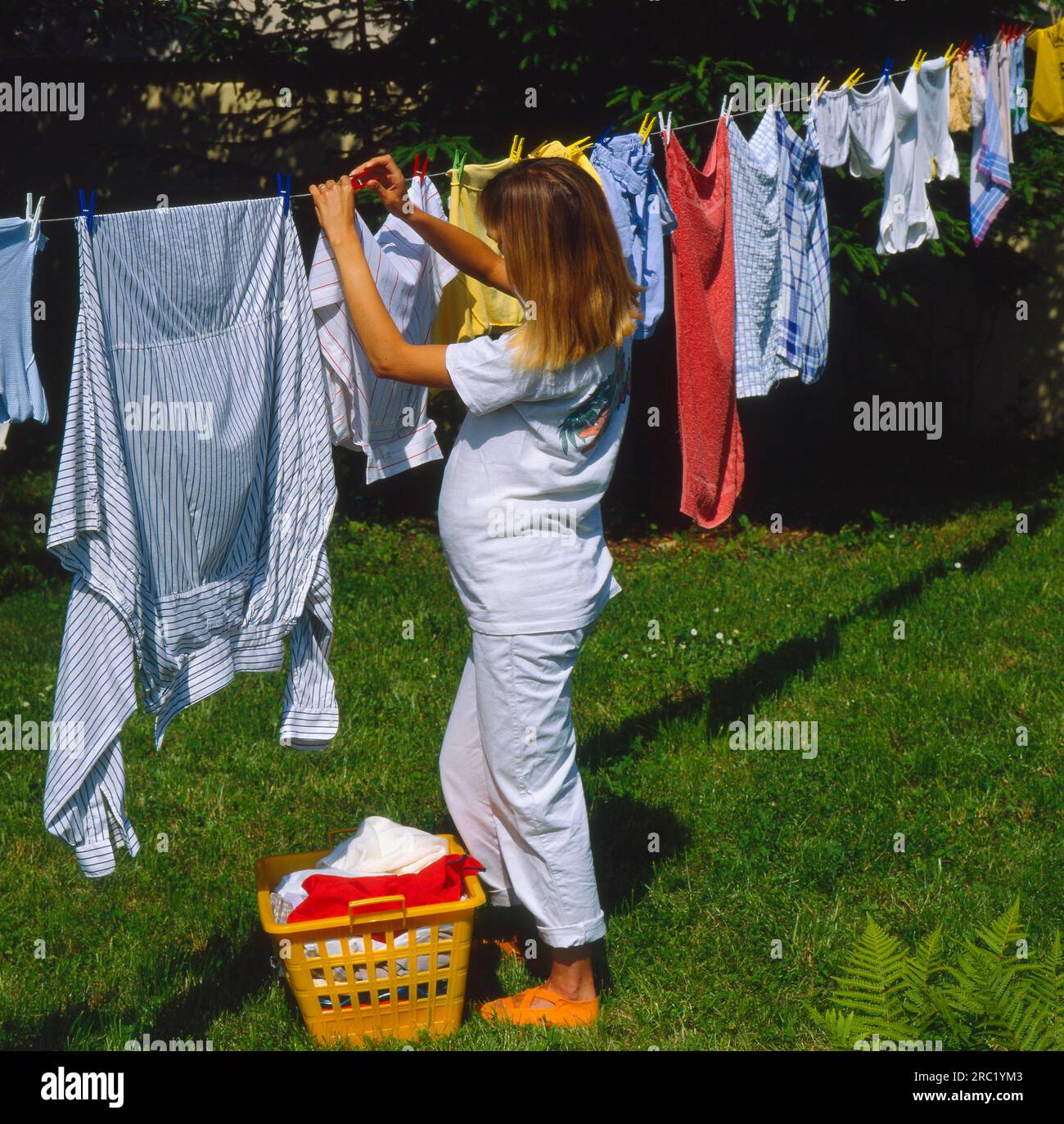 Pregnant woman hangs laundry on the line in the garden Stock Photo