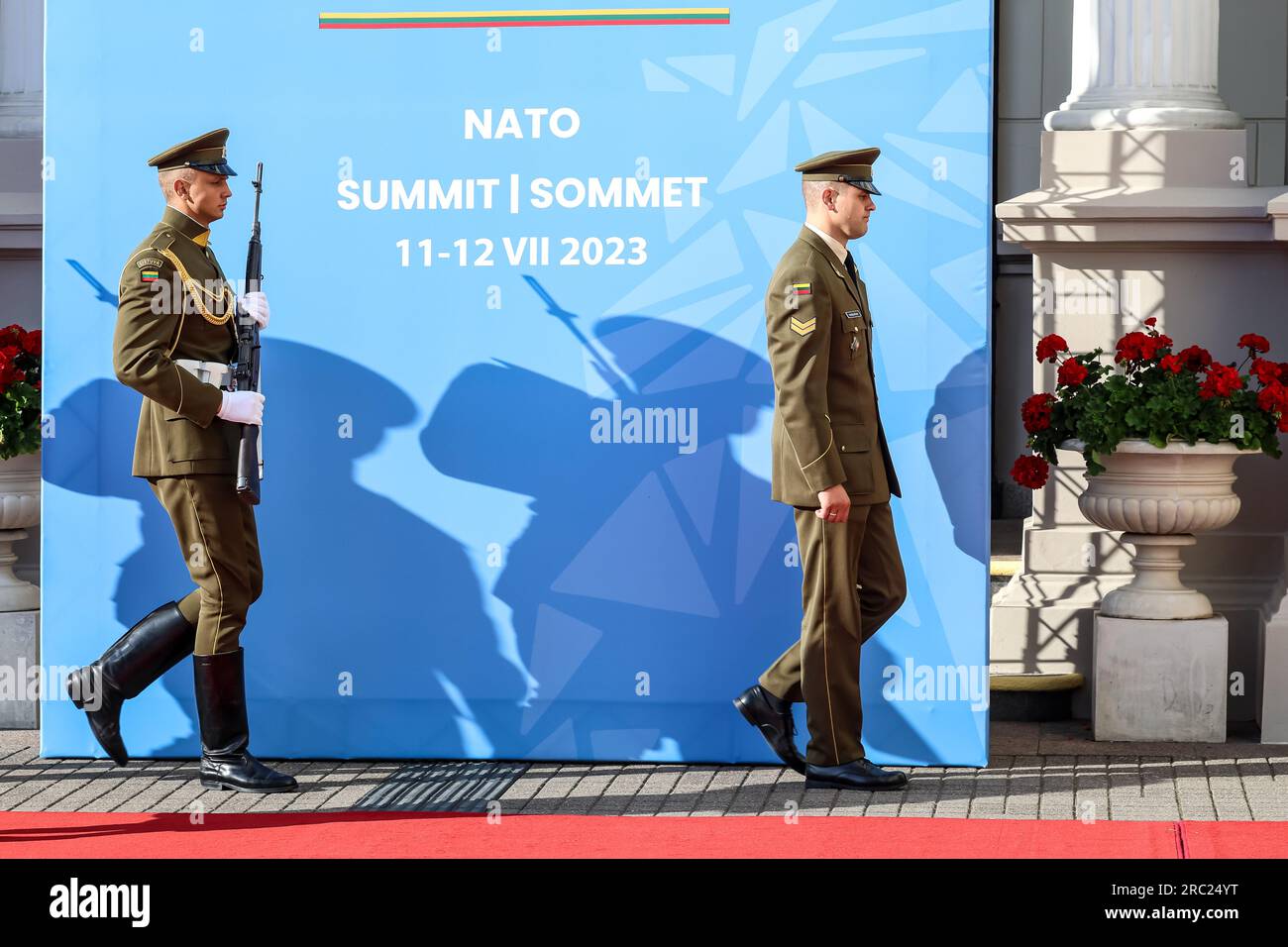 Vilnius, Lithuania. 11th July, 2023. Soldiers walk in front of a billboard during the high level NATO summit. The President of Lithuania hosts the dinner for world leaders at the Presidential Palace. The summit agenda covers Ukraine's bid to join the organisation, the accession process of Sweden, boosting arms stockpiles and reviewing plans. Credit: SOPA Images Limited/Alamy Live News Stock Photo