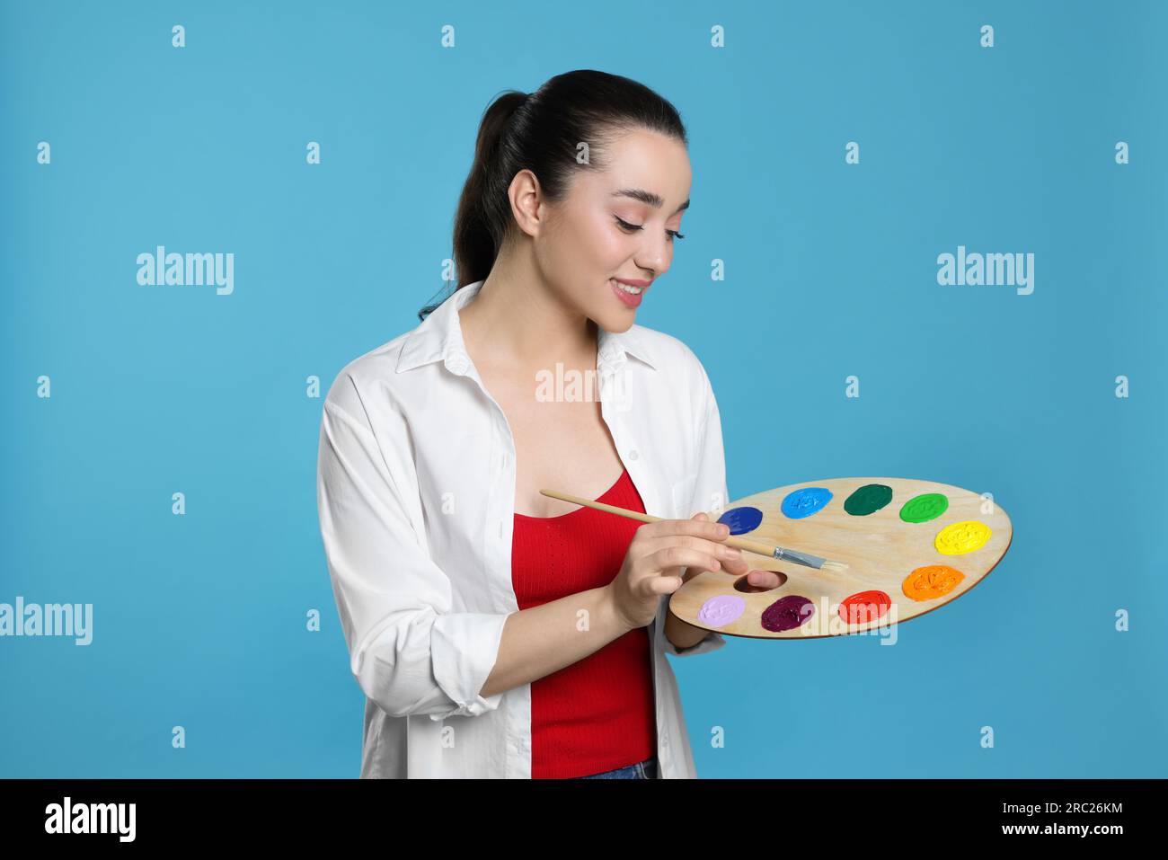 Woman with painting tools on light blue background. Young artist Stock ...