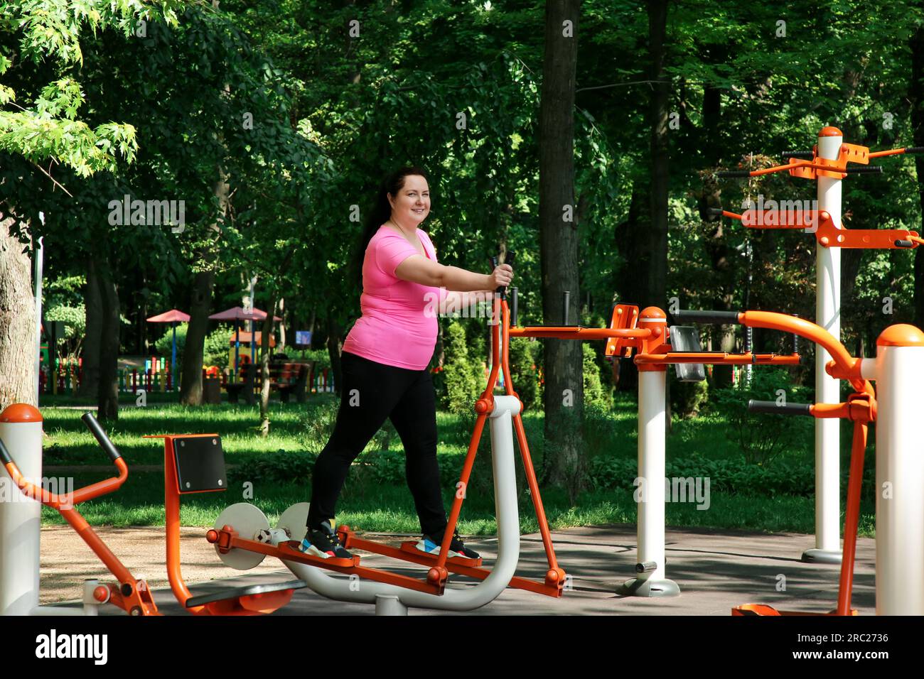 Overweight woman doing exercise with air walker in park Stock Photo