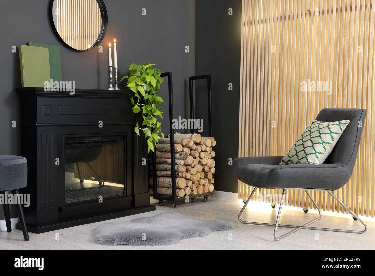 Stylish room with beautiful fireplace, houseplant and comfortable chair