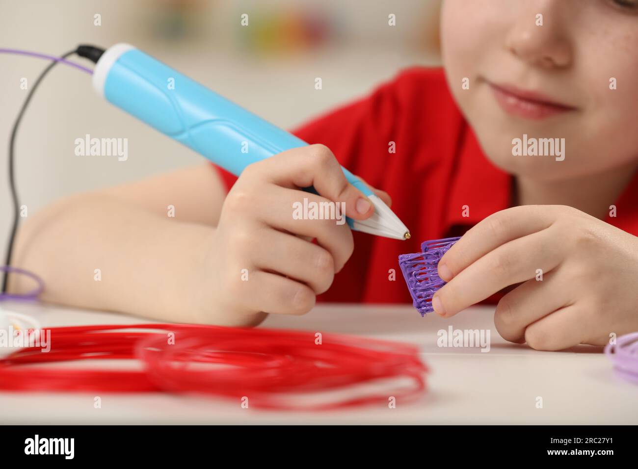 Boy drawing with stylish 3D pen at white table, closeup Stock Photo