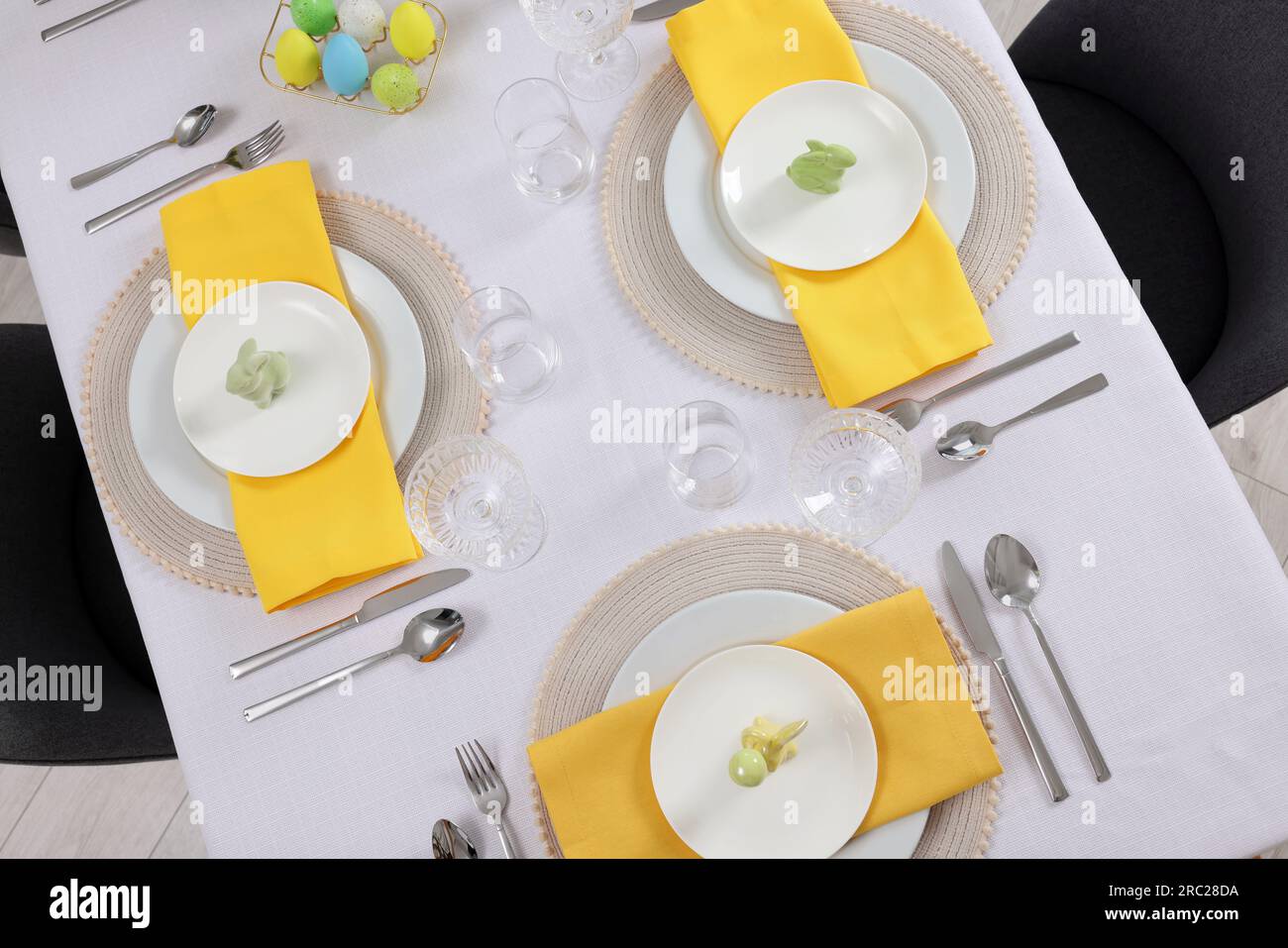 Festive table setting with glasses, painted eggs and plates, view from above. Easter celebration Stock Photo