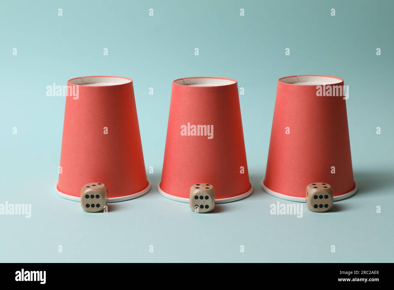 Three red cups and dices on light blue background. Thimblerig game ...