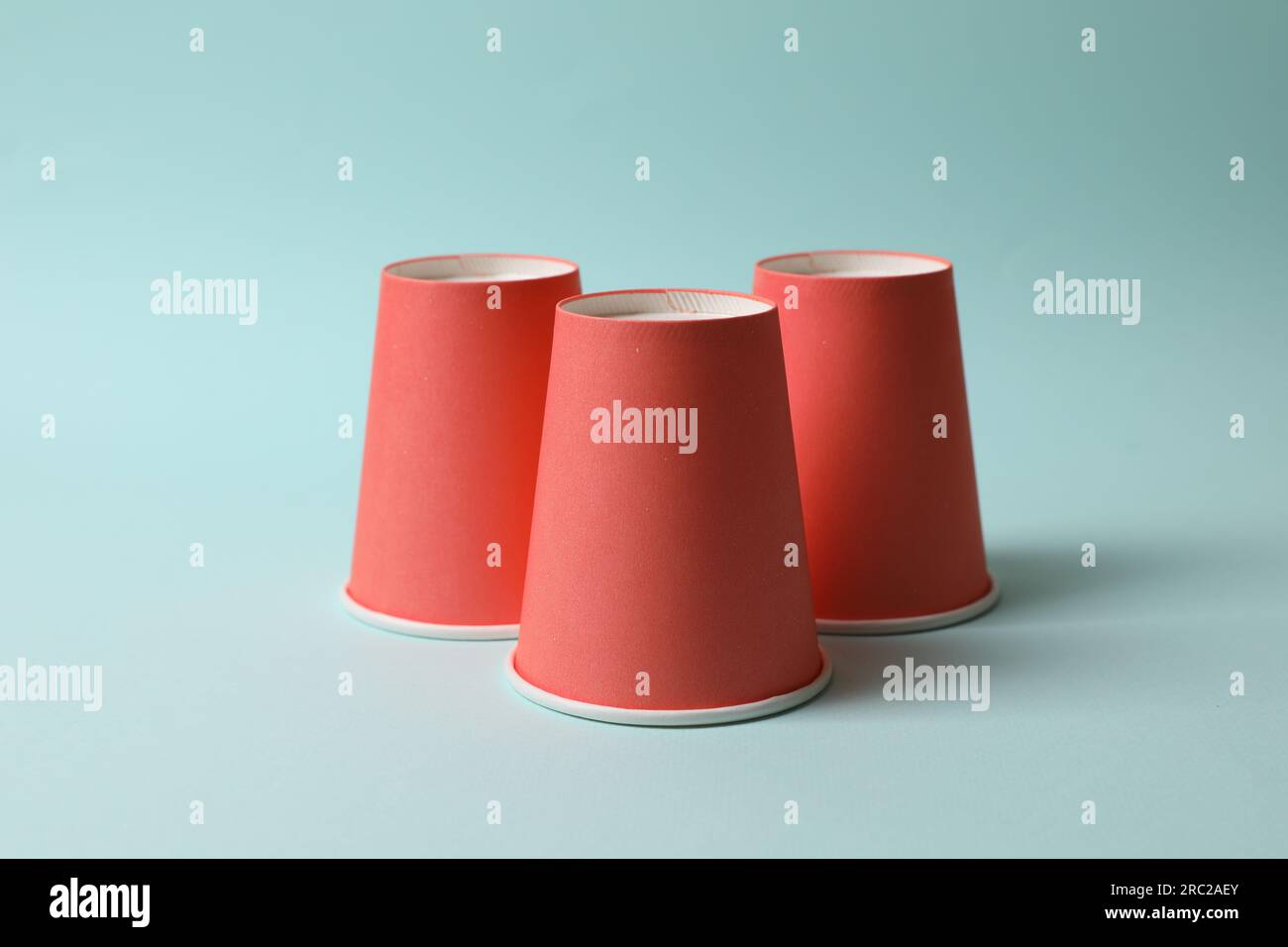 Three red cups on light blue background. Thimblerig game Stock Photo ...