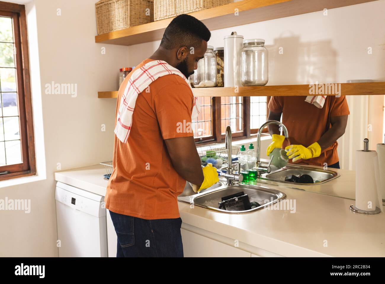 https://c8.alamy.com/comp/2RC2B34/focused-african-american-man-with-towel-on-arm-washing-dishes-in-kitchen-2RC2B34.jpg