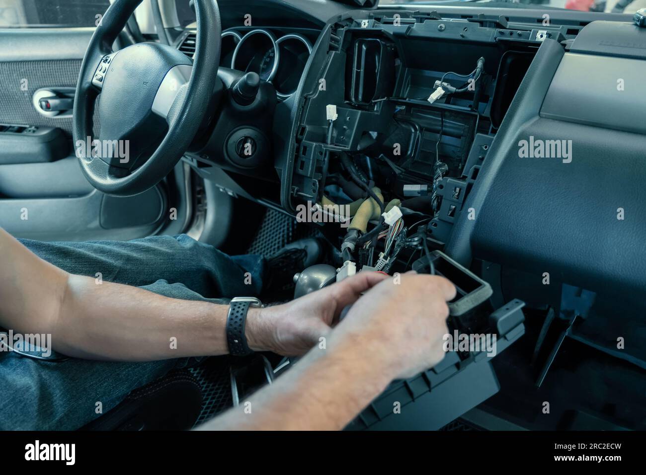 Auto in Car Service, process of installing radio sound system. Auto electric hands on dashboard fixing problem close-up. Stock Photo