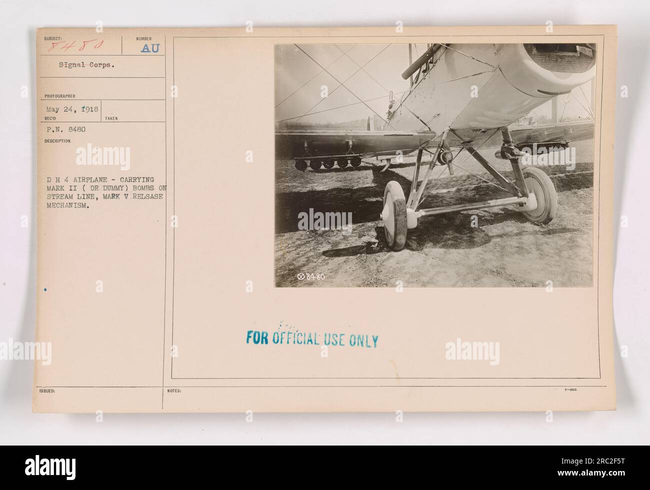 This image, labeled 111-SC-8480 and taken by the Signal Corps photographer on May 24, 1918, shows a DH 4 airplane equipped with Mark II (DR Dummy) bombs on a stream line and a Mark V release mechanism. The notes indicate that it is for official use only. Stock Photo
