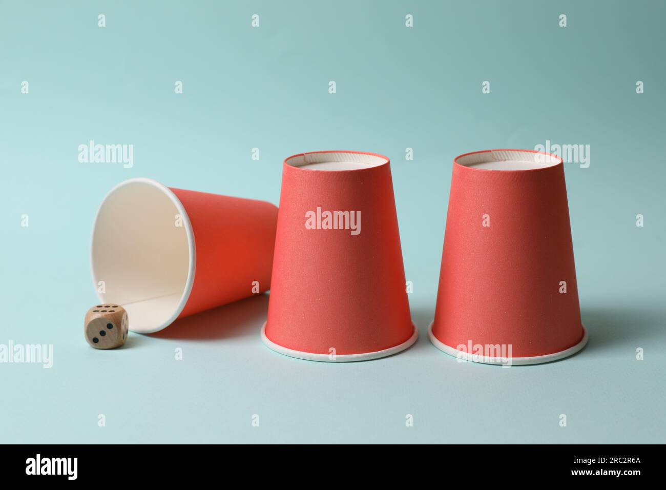 Three red cups and dice on light blue background. Thimblerig game Stock ...