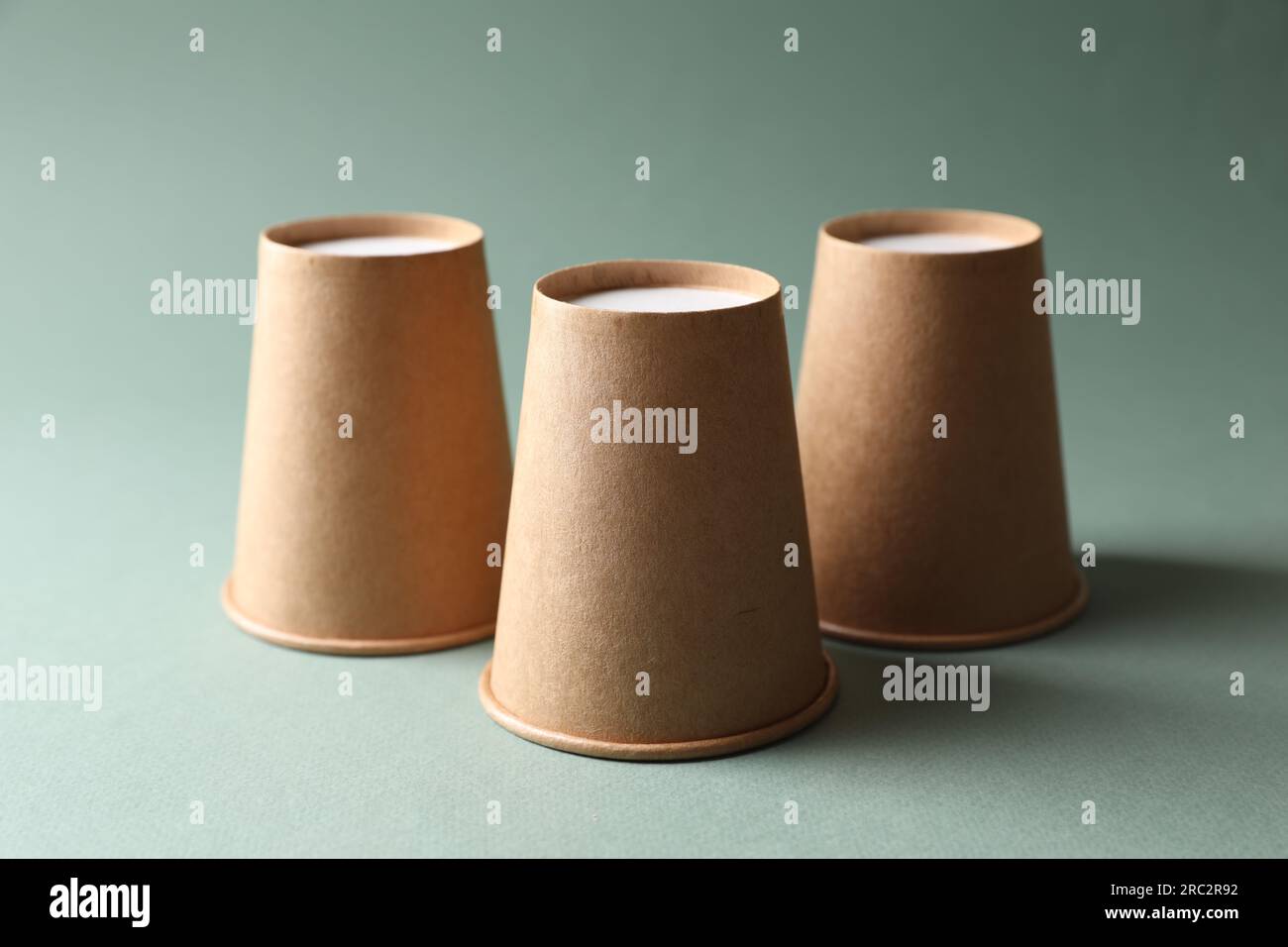 Three paper cups on pale olive background. Thimblerig game Stock Photo ...