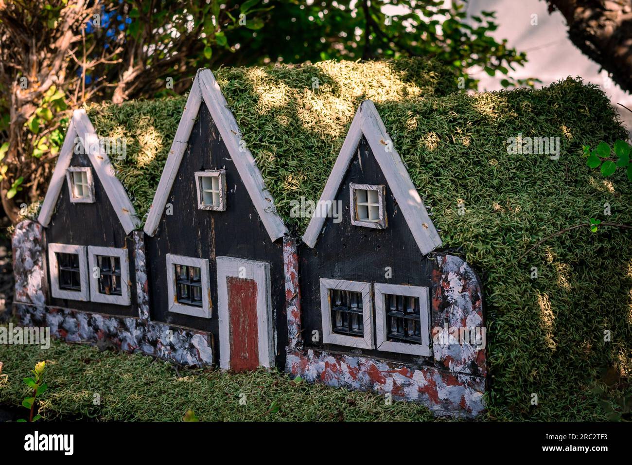 Three small black wooden elf houses with green moss roof, typical for Iceland. Stock Photo