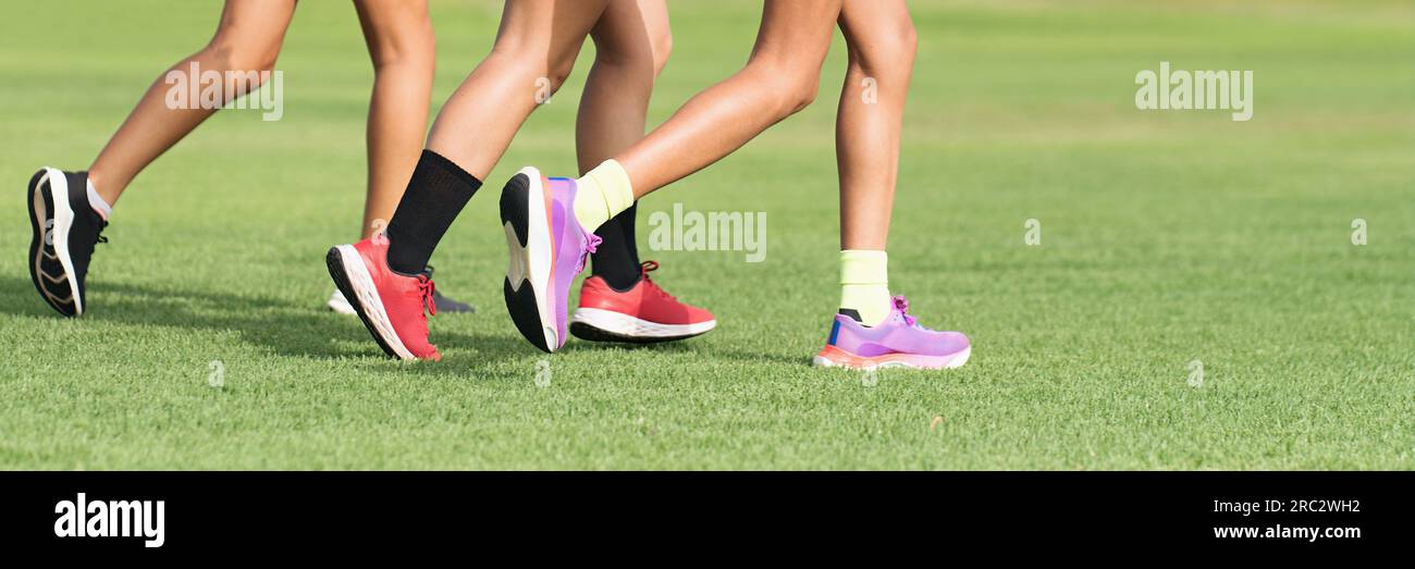 Three female athletes runners, athletes feet running on grass. Female y