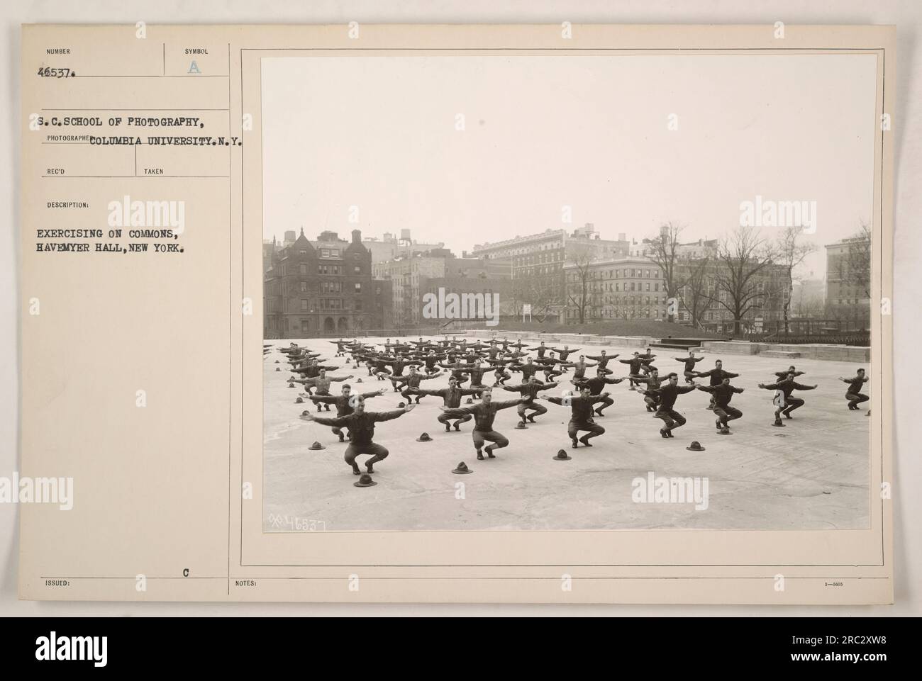 Soldiers participating in physical exercise on the commons near Havemyer Hall in New York during World War One. This photograph was taken by the School of Photography at Columbia University. In the image, the soldiers can be seen following a structured exercise routine. The photograph is labeled with the number 46537. Stock Photo