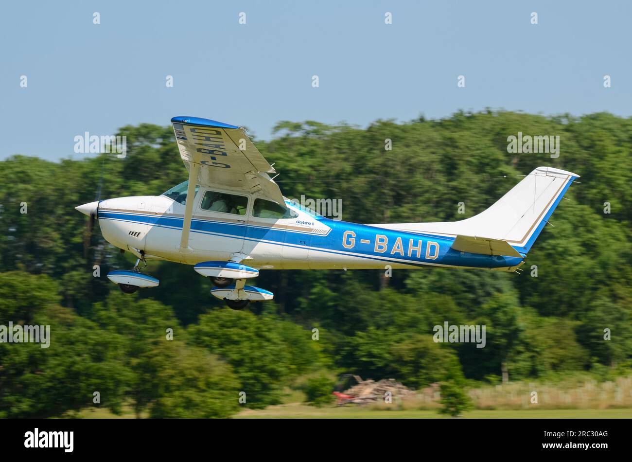 Cessna 182P Skylane plane taking off at Heveningham countryside grass airstrip in Suffolk, UK after fly-in event. Tree lined grass runway. Stock Photo