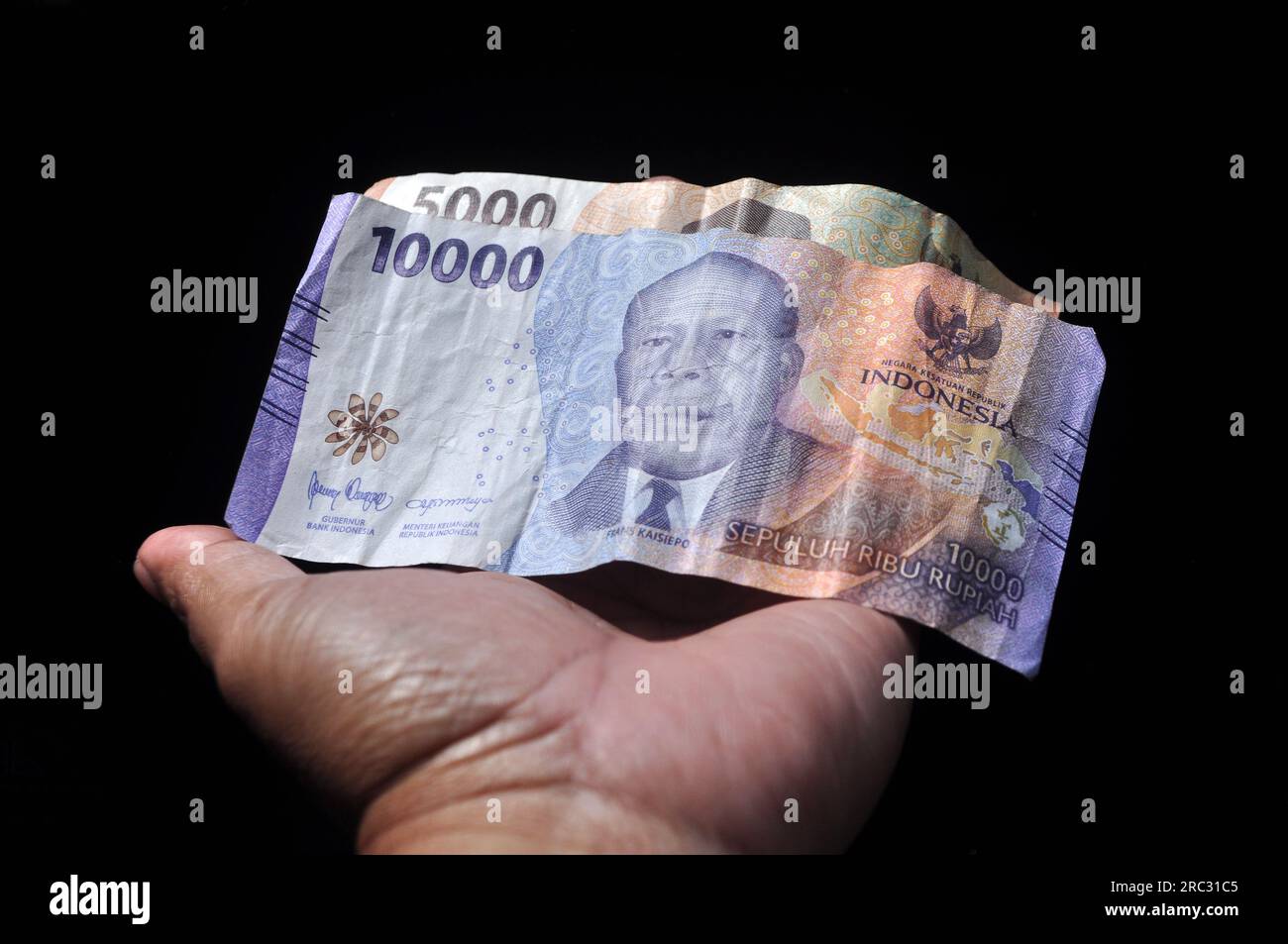 Indonesian rupiah banknotes in hand black background Stock Photo - Alamy