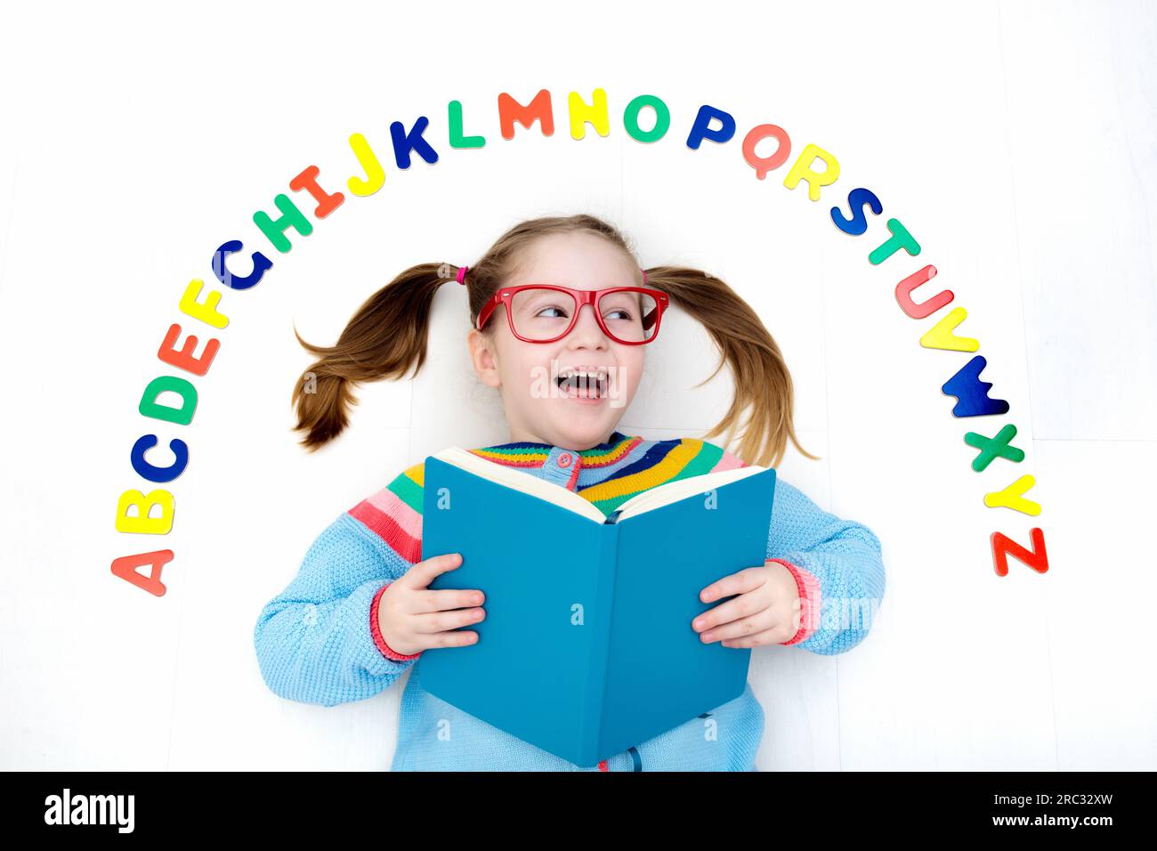 Happy preschool child learning to read and write playing with colorful roman alphabet letters