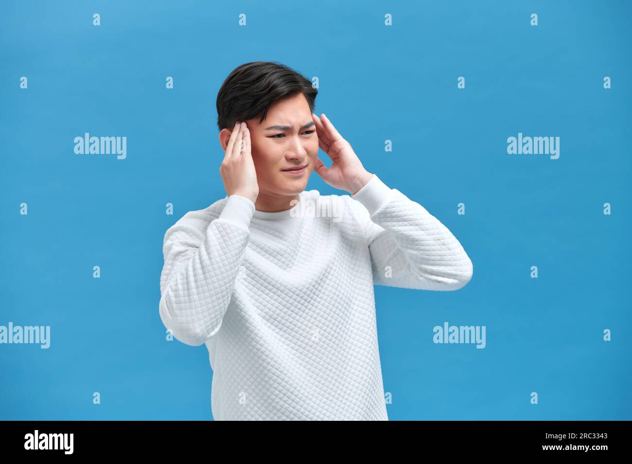 young Asian man holds head while dizzy on isolated background Stock Photo