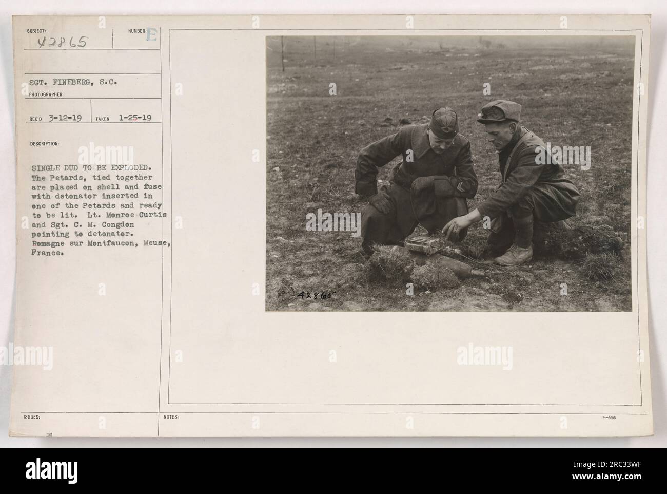 Sgt. Fineberg took a photograph on January 25, 1919, showing a hibere single dud being prepared for detonation. The Petards, tied together, were placed on a shell with a fuse and a detonator inserted into one of them. Lt. Monroe Curtis and Sgt. C. M. Congdon can be seen pointing to the detonator. The image was taken in Remagne sur Montfaucon, Meuse, France. Stock Photo