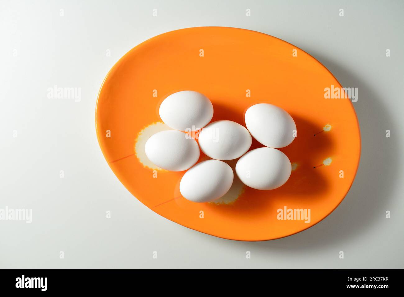 Fresh white eggs on an orage plate. White background. Stock Photo