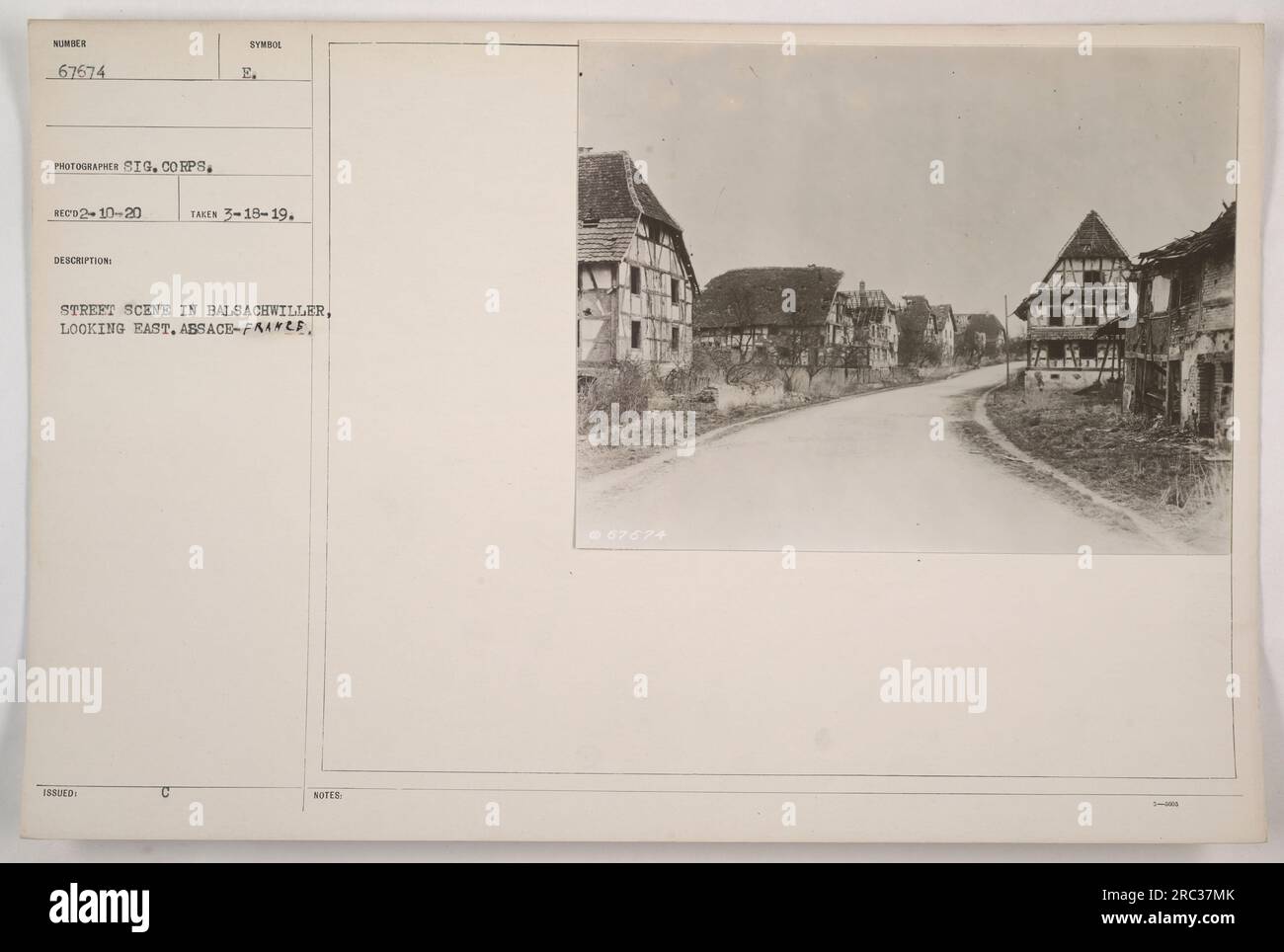 A photograph of a street scene in Balsachwiller, Alsace, France, taken on March 18, 1919, by a photographer of the Signal Corps. The image shows a view looking east, with buildings and people visible in the photograph. The image is numbered 67674 and bears the symbol issued by the Signal Corps. Note: @67674. Stock Photo