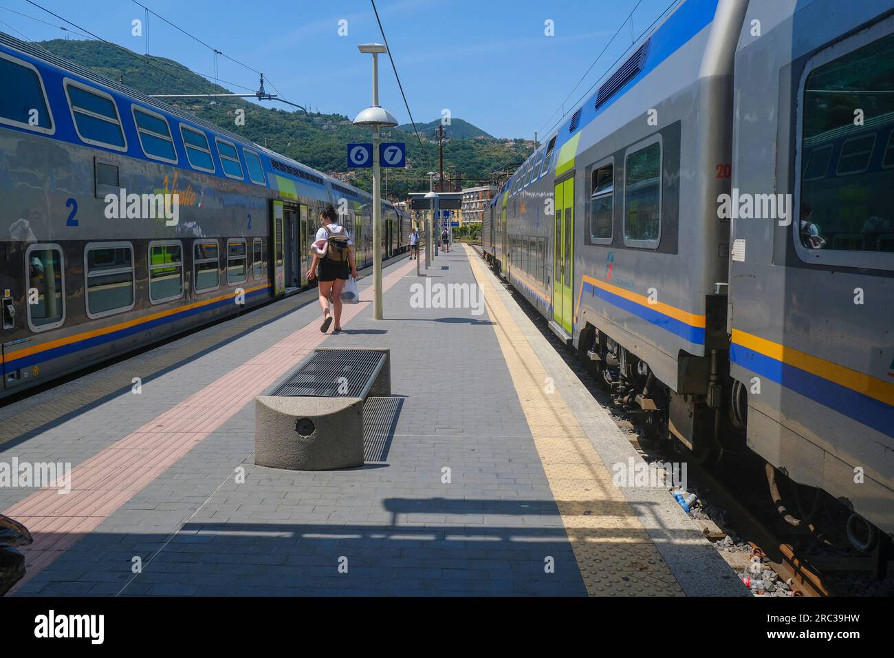 June 2023 La Spezia, Italy: Railway station, passengers with suitcases and fast trains across the mountains landscape Stock Photo