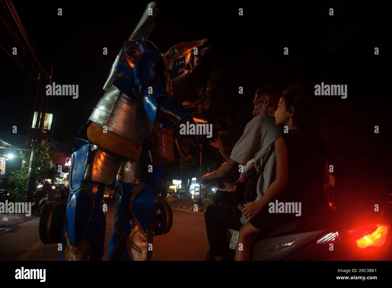 Medan City, Indonesia. 11th July, 2023. A fictional robot character and protagonist of The Transformers movie series, Optimus Prime is seen greeting motorists who crossover AR Hakim street of Medan City, North Sumatra, Indonesia on July 11, 2023. That street entertainment action is played by an street artist Heri which wearing a robotic outfit made of foam and helped by his colleague, Dafa. Photo by Sutanta Aditya/ABACAPRESS.COM Credit: Abaca Press/Alamy Live News Stock Photo