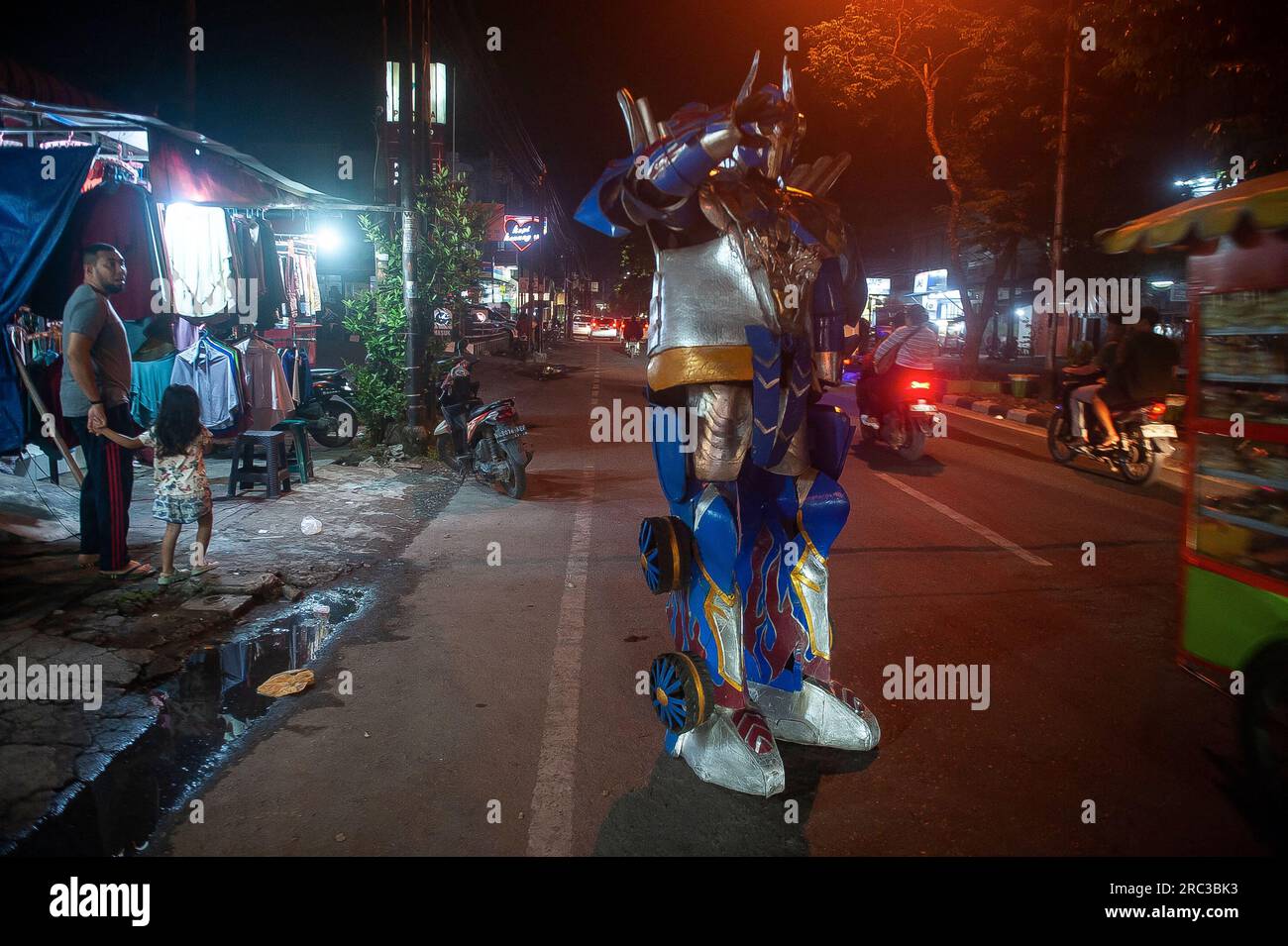 Medan City, Indonesia. 11th July, 2023. A fictional robot character and protagonist of The Transformers movie series, Optimus Prime is seen greeting motorists who crossover AR Hakim street of Medan City, North Sumatra, Indonesia on July 11, 2023. That street entertainment action is played by an street artist Heri which wearing a robotic outfit made of foam and helped by his colleague, Dafa. Photo by Sutanta Aditya/ABACAPRESS.COM Credit: Abaca Press/Alamy Live News Stock Photo