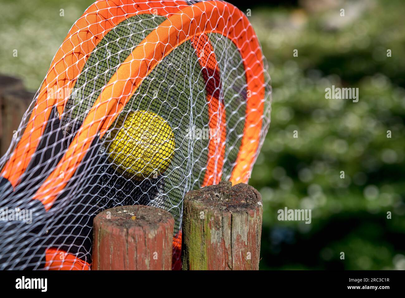 Detail image of tennis rackets and ball green background and quite blurred, on a very sunny day. Small depth of field. Beautiful contrast of texture. Stock Photo