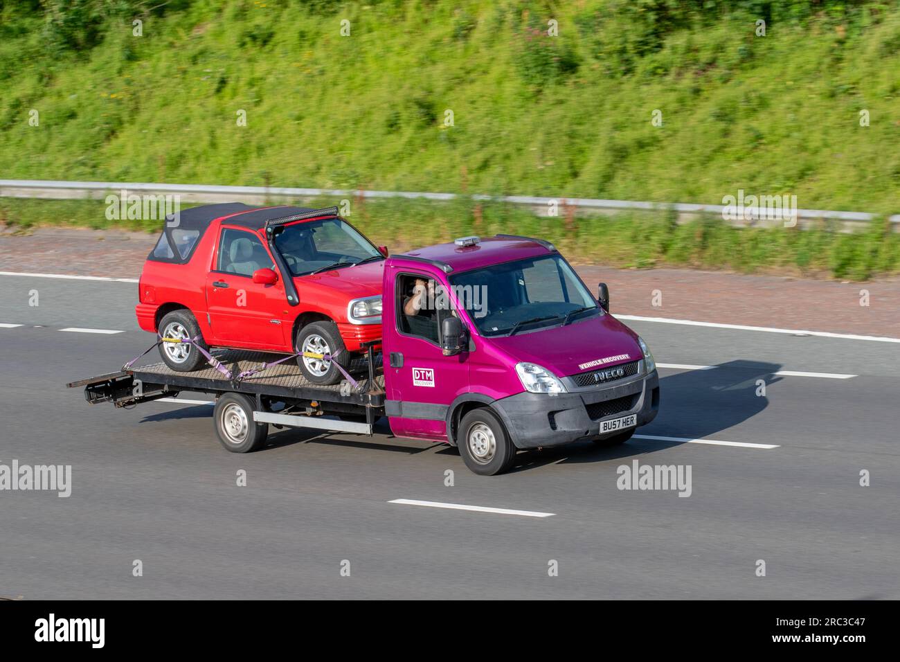 DTM Vehicle Recovery. 2010 Iveco Daily 35S11 Mwb 35S11 Hpi MWB LCV High Roof Panel Van Diesel 2287 cc, carrying 1994 90s red Mitsubishi Shogun small SUV; travelling on the M6 motorway in Greater Manchester, UK Stock Photo