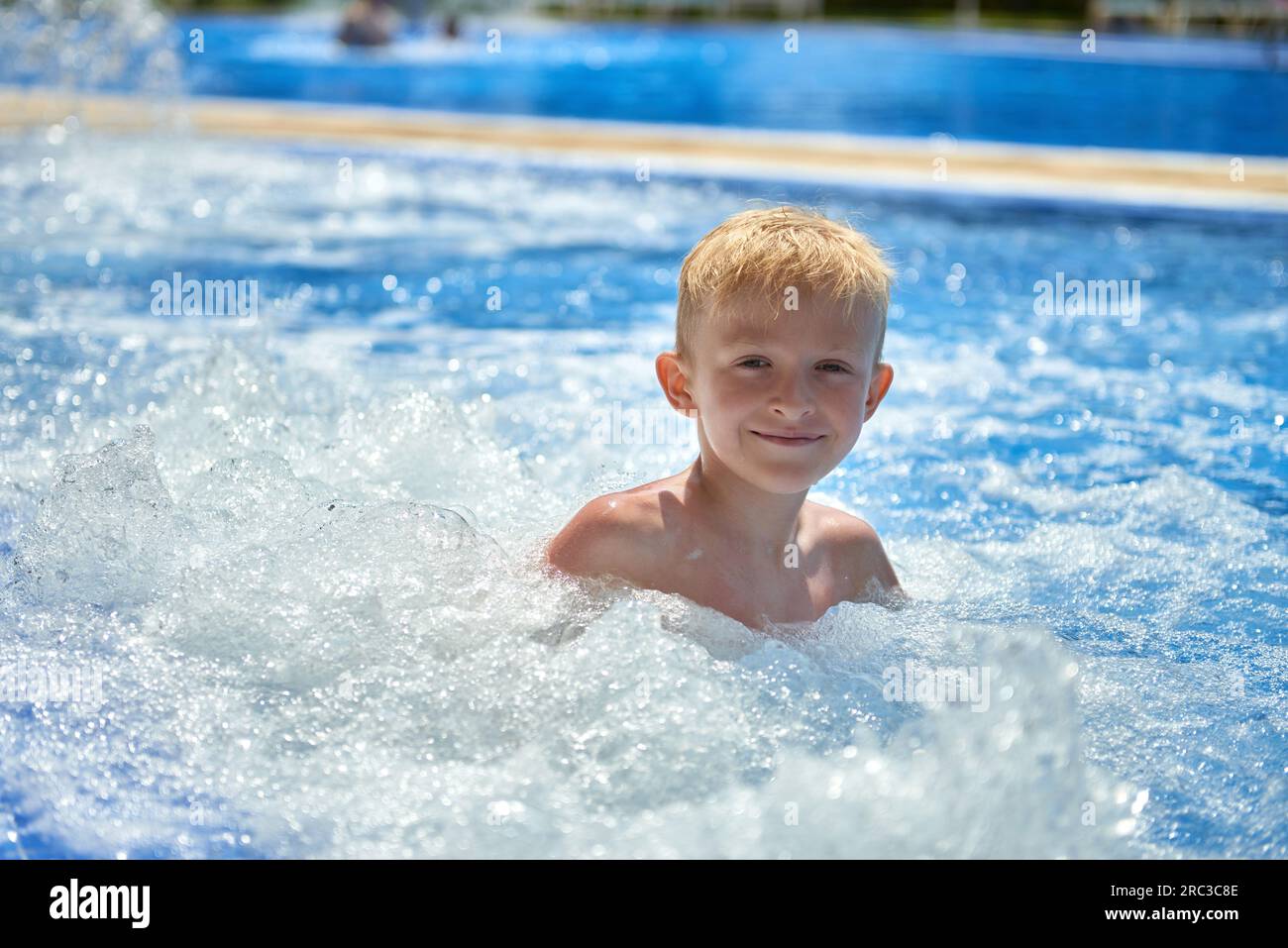 Young boy kid child eight years old splashing in swimming pool having