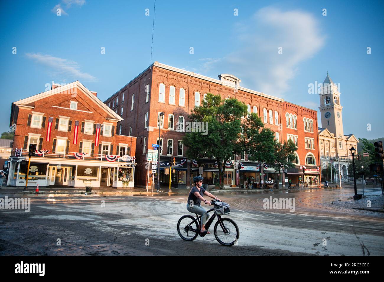 11th July 2023.  Montpelier, USA.  A bicyclist pedals through the intersection of State and Main streets  in Montpelier, VT, USA, after floodwaters from the Winooski River receded leaving muddy streets and an imminent major cleanup following flooding that began 10 July 2023. Credit: John Lazenby/Alamy Live News. Stock Photo