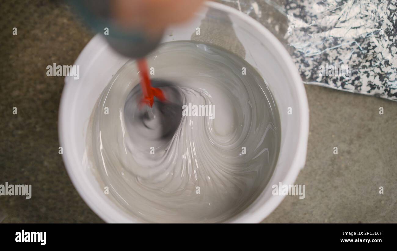 Mixing mortar, floor, in a bucket. A man makes cement with a