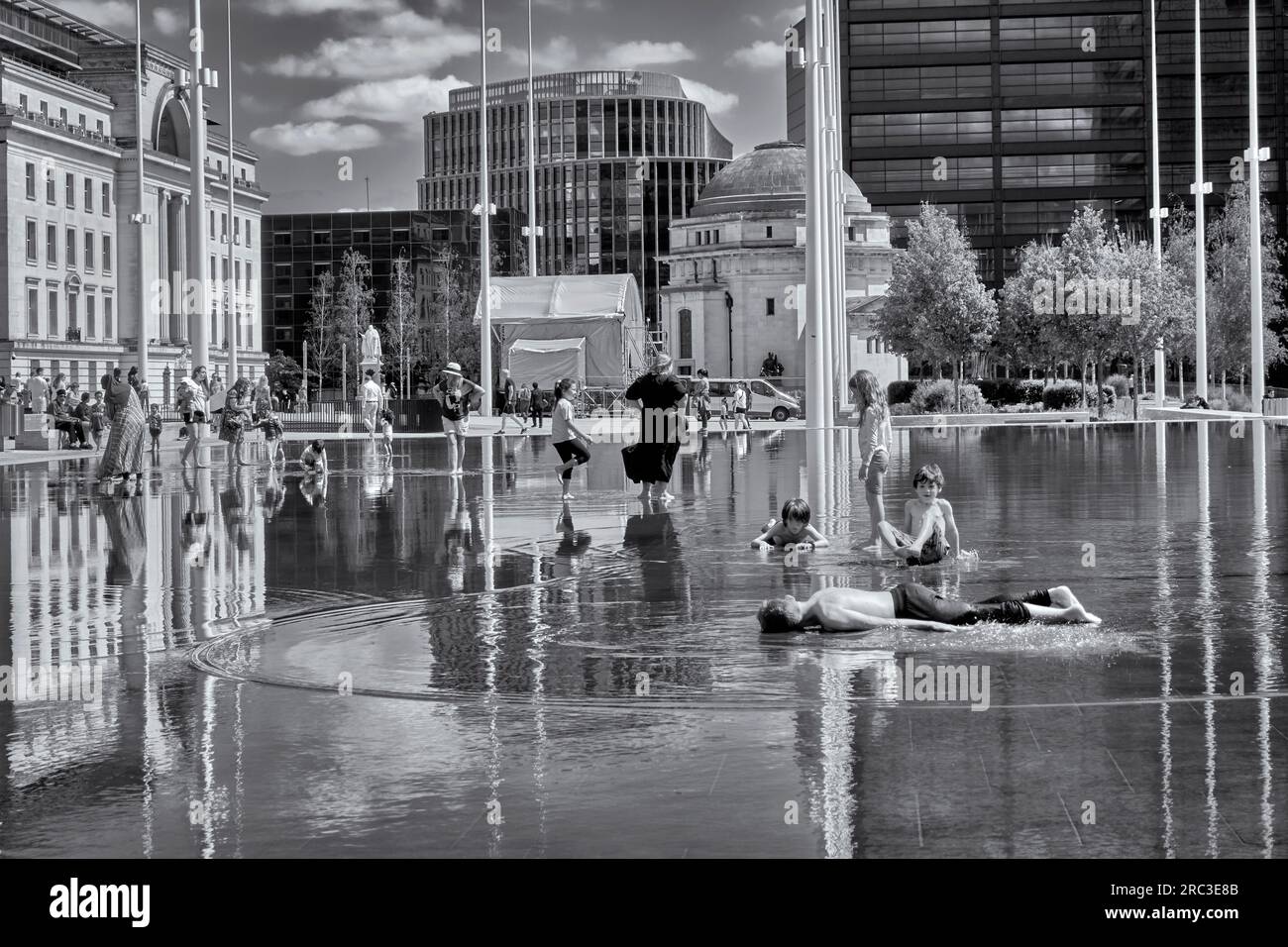 Centenary Square, Birmingham with children cooling off in the water from a summer heatwave, England UK Black and white photography Stock Photo