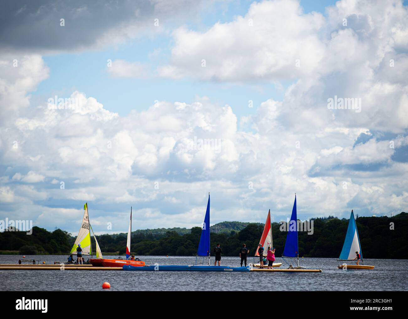 Castle Semple, Lochwinnoch, Scotland, UK. 12th July 2023. Watersport enthusiasts are undeterred by the changeable weather conditions. Castle Semple is used by people of all ages to paddle board and learn sail. Stock Photo