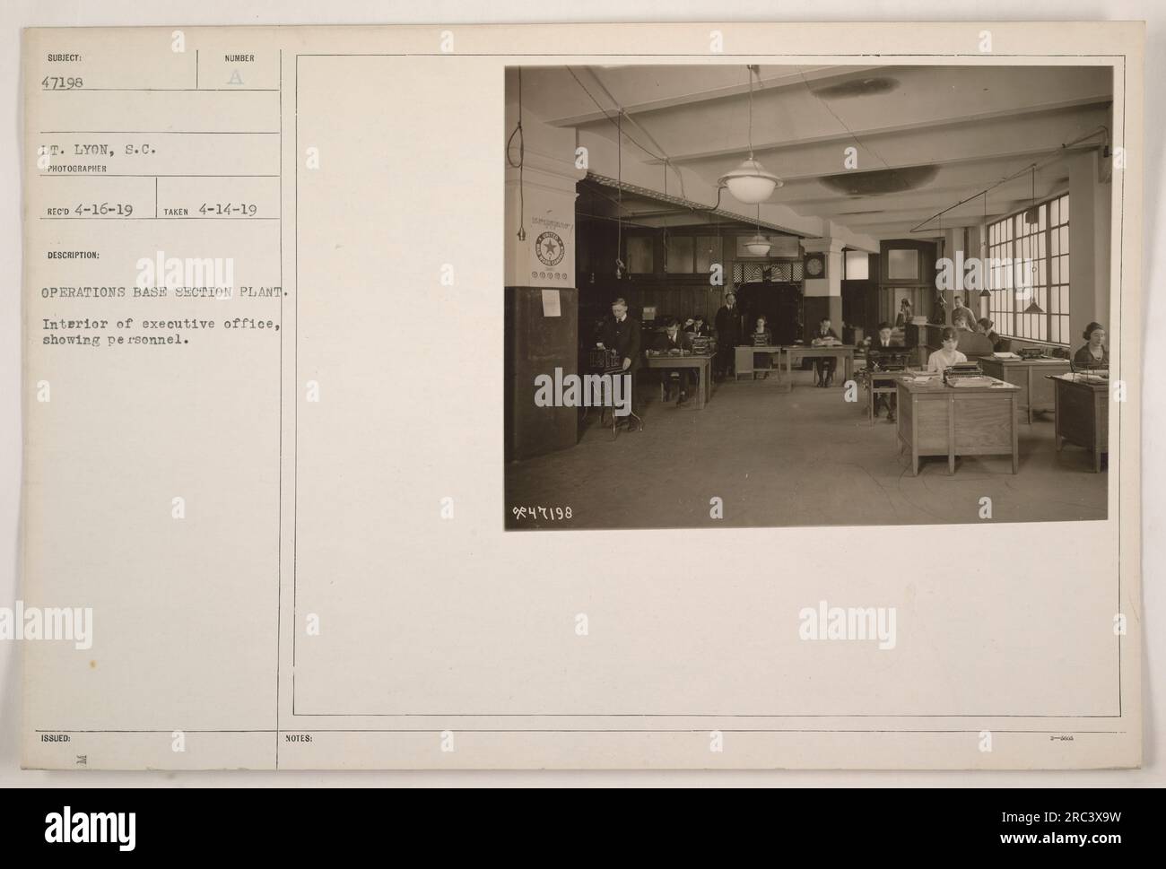Interior of executive office at Operations Base Section Plant in New York. The photograph shows personnel working in the office. The image was taken by Lt. Lyon on April 14, 1919, and is numbered as subject 47198. Includes Bud H's notes. Stock Photo
