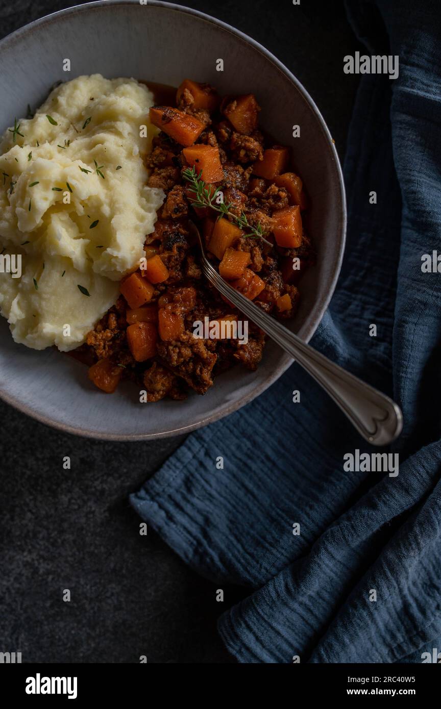 Tasty ground beef stew with carrots and vegetables. Served with mashed potatoes on a plate from above Stock Photo