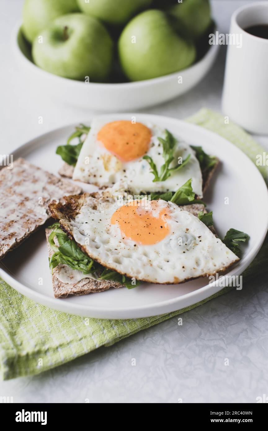 Vegetarian breakfast sandwich with organic crispbread, arugula and fried eggs. Stock Photo