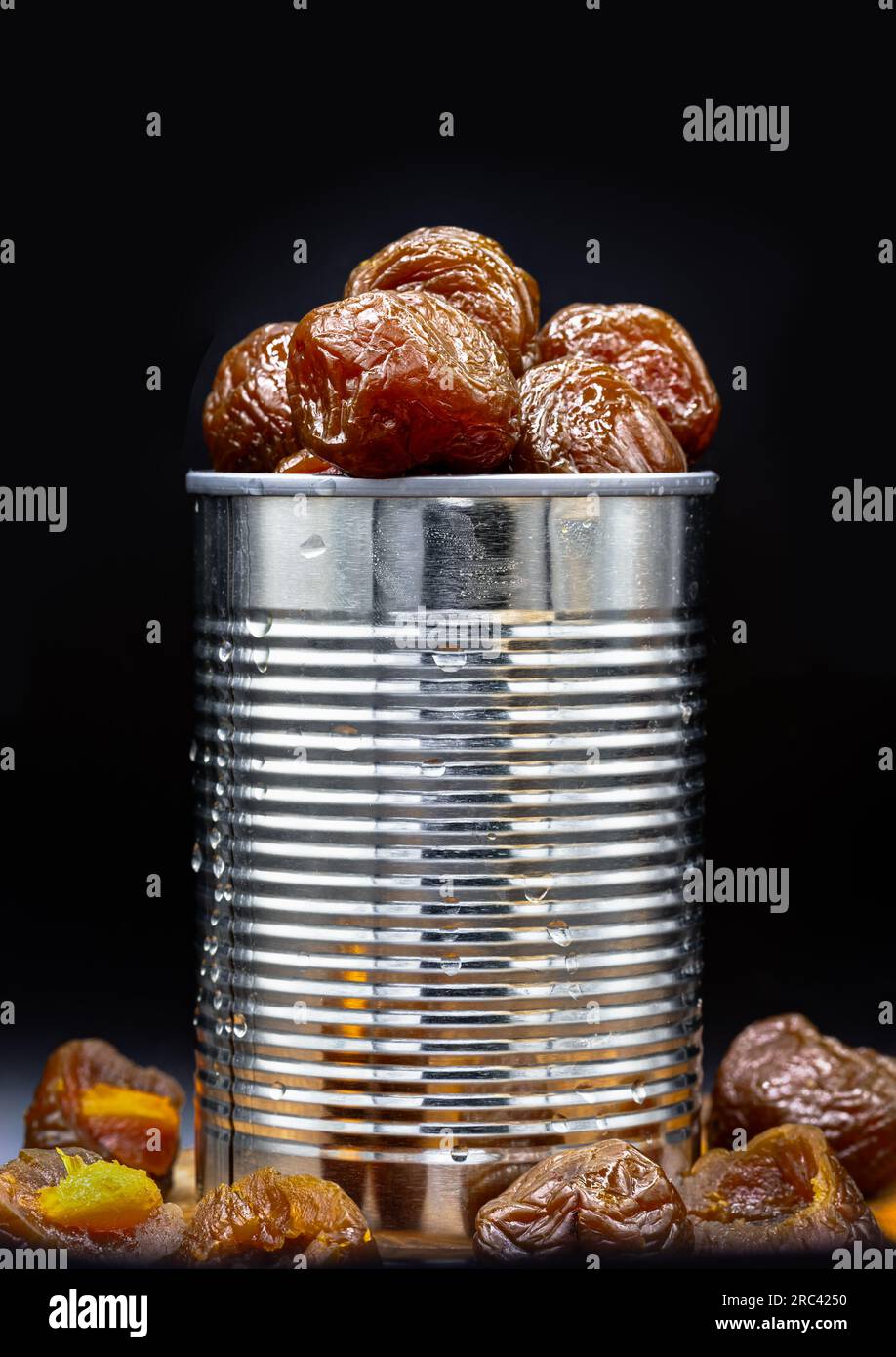 Flavored preserved chinese plums (Preserved fruits) in tin can on dark background. Its flavour has sour, salty and sweet taste. Space for text, Select Stock Photo