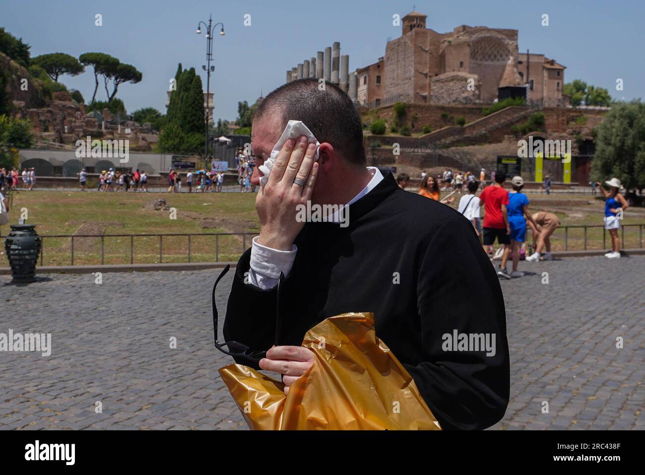 Rome, Italy. 12 July 2023 A priest wipes the sweat from his face as