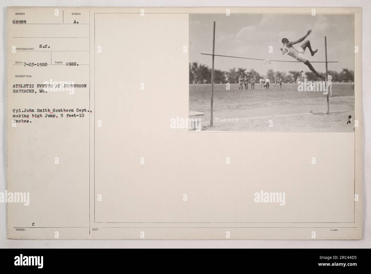 Cpl. John Smith, serving in the Southern Department, participates in athletic events at Jefferson Barracks, Missouri. In this photograph taken on July 23, 1920, Cpl. Smith is seen making a high jump, reaching a height of 5 feet and 10 inches. The photograph is labeled as number 68989 and was taken by photographer ECD in 1920. The description mentions it was issued by S.C. Synol and captures the athletic events at Jefferson Barracks. Stock Photo