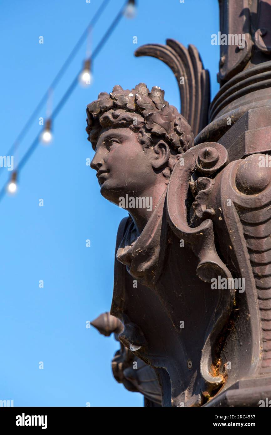 Fragment from a vintage ornate lamppost with face figure with an aok leaves wreath in Geneva, Switzerland. Stock Photo