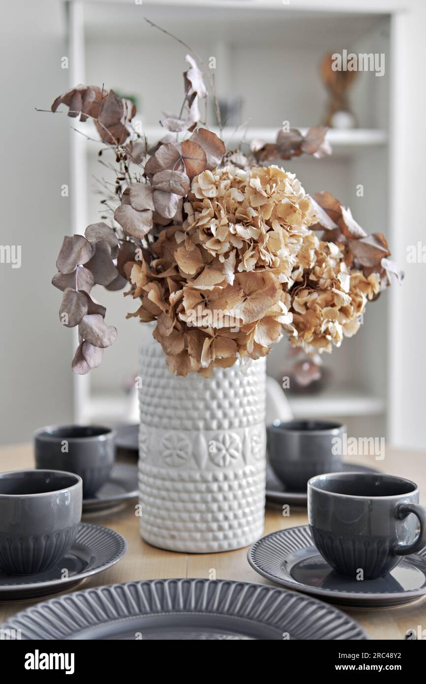 Pretty flowers in vase on a dinning table with served coffee or tea