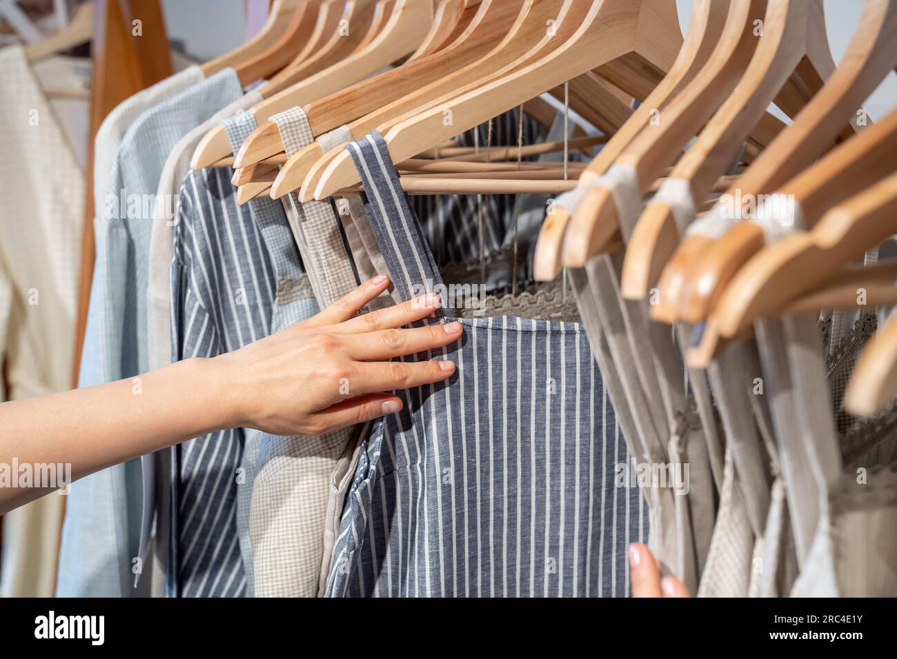Organic cotton clothing hanging on rack, woman buying clothes made from