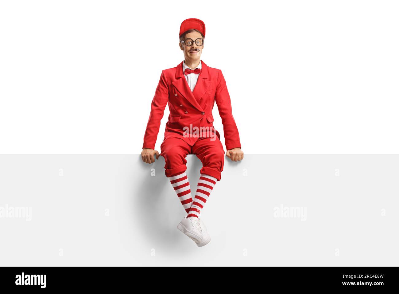 Entertainment performer in red suit sitting on a blank panel isolated on white background Stock Photo