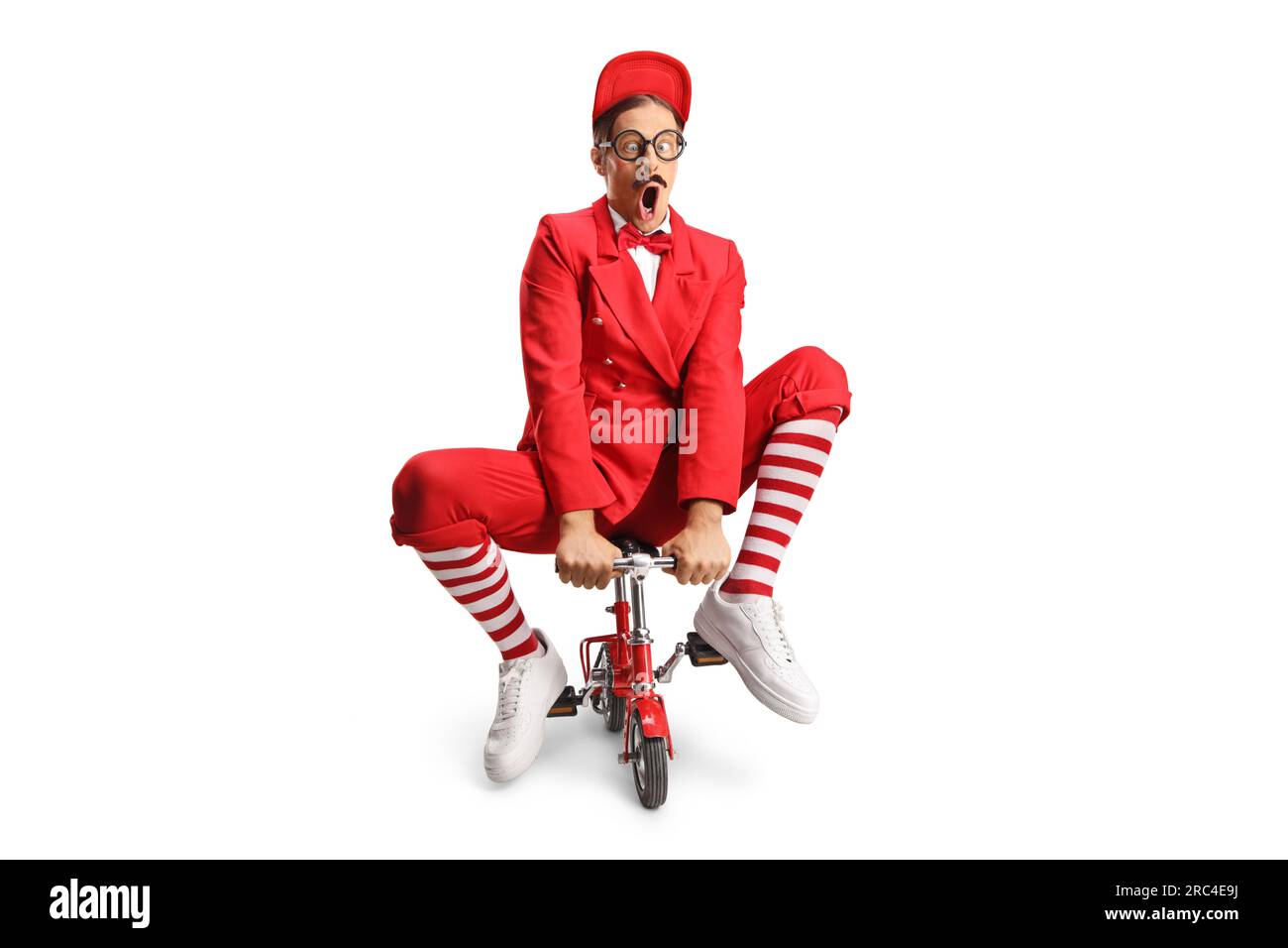 Funny entertainer riding a small red bike isolated on white background Stock Photo