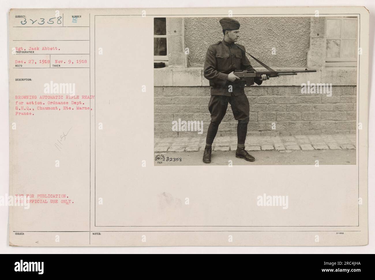 Sgt. Jack Abbott standing next to a Browning Automatic Rifle (BAR) in readiness for action. The photograph was taken on November 9, 1918, at the Ordnance Dept., G.H.Q. in Chaumont, Hte. Marne, France. It is marked with the reference number 32358 and was not intended for publication, only for official use. Stock Photo