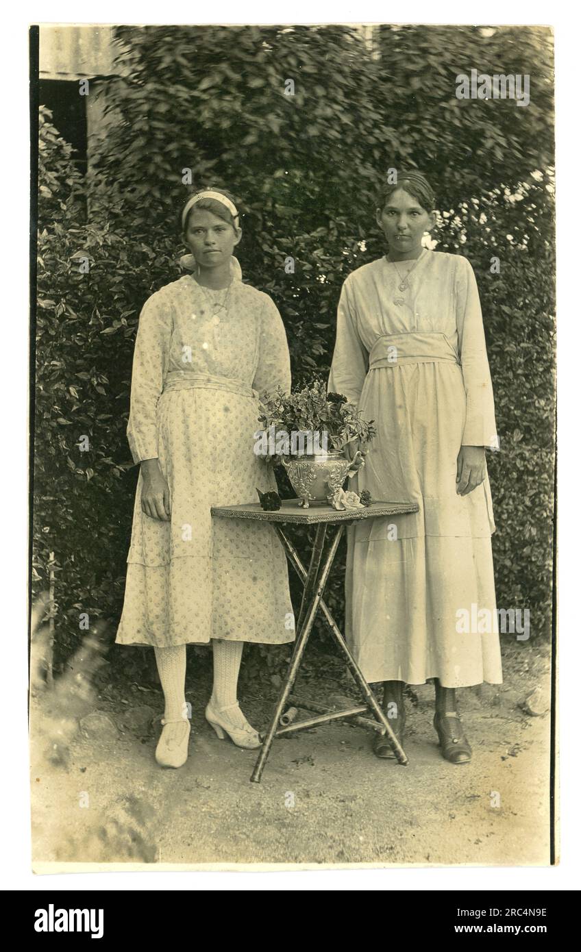 Original early 1920's era postcard of 2 pretty, serious looking teenage sisters of mixed aboriginal or Torres Strait Island descent called Lillie and Florrie wearing Western summer clothes, fostered into white families, removed from their family by 'removalists' who were mostly white male missionaries, patrol officers and police officers -  this scandal is known as the Stolen Generations or Stolen Children, Australia Stock Photo