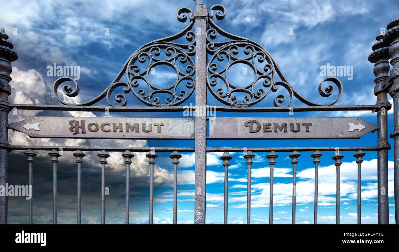 An image with a signpost pointing in two different directions in German. One direction points to humility, the other points to arrogance. Stock Photo