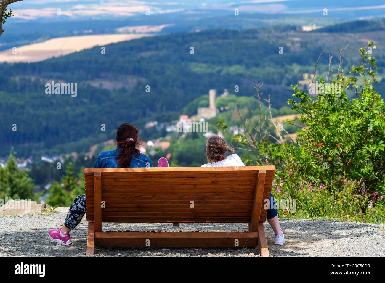 Schmitten, Germany. 12th July, 2023. Two women sit on a bench and look at the ruins of Reifenberg Castle. Numerous people visit the Feldberg plateau in fresh temperatures and gusty winds. Credit: Andreas Arnold/dpa/Alamy Live News Stock Photo